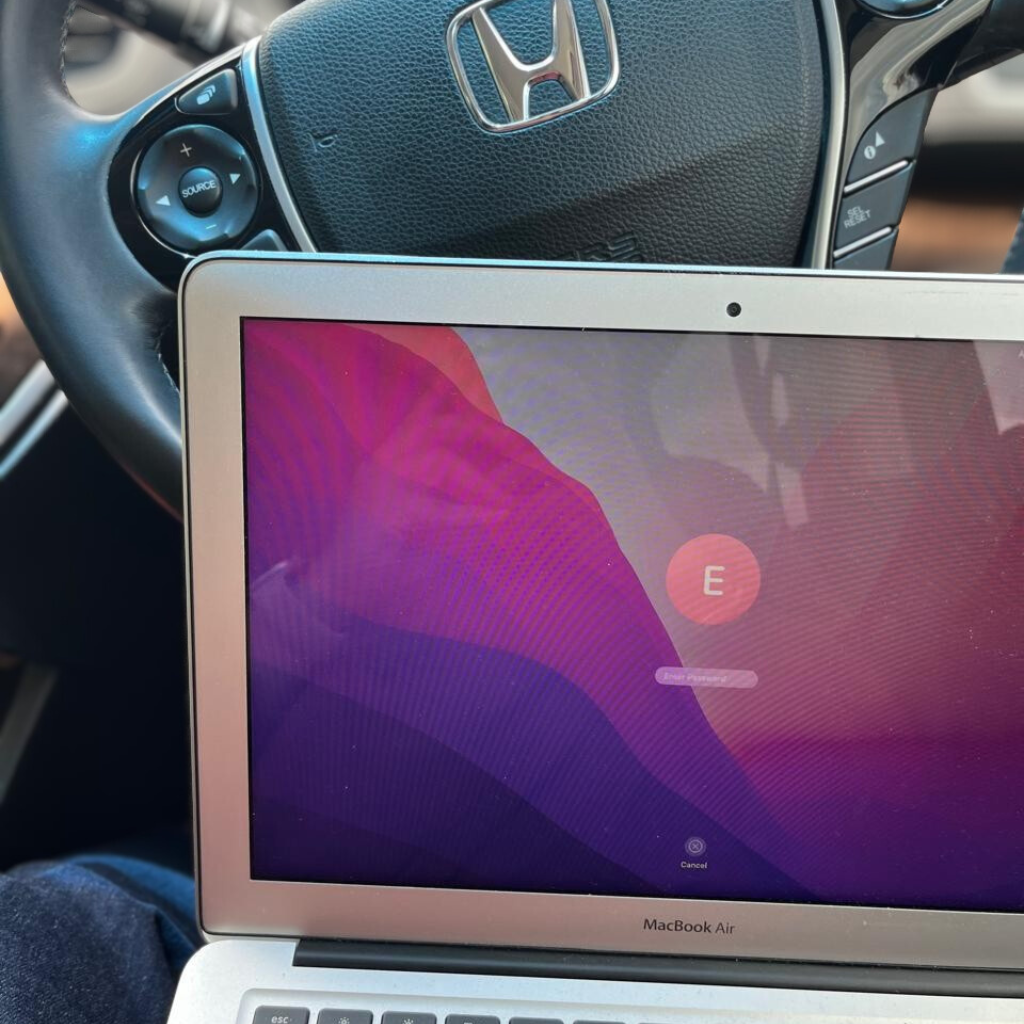 Laptop on car dashboard with a login screen visible.