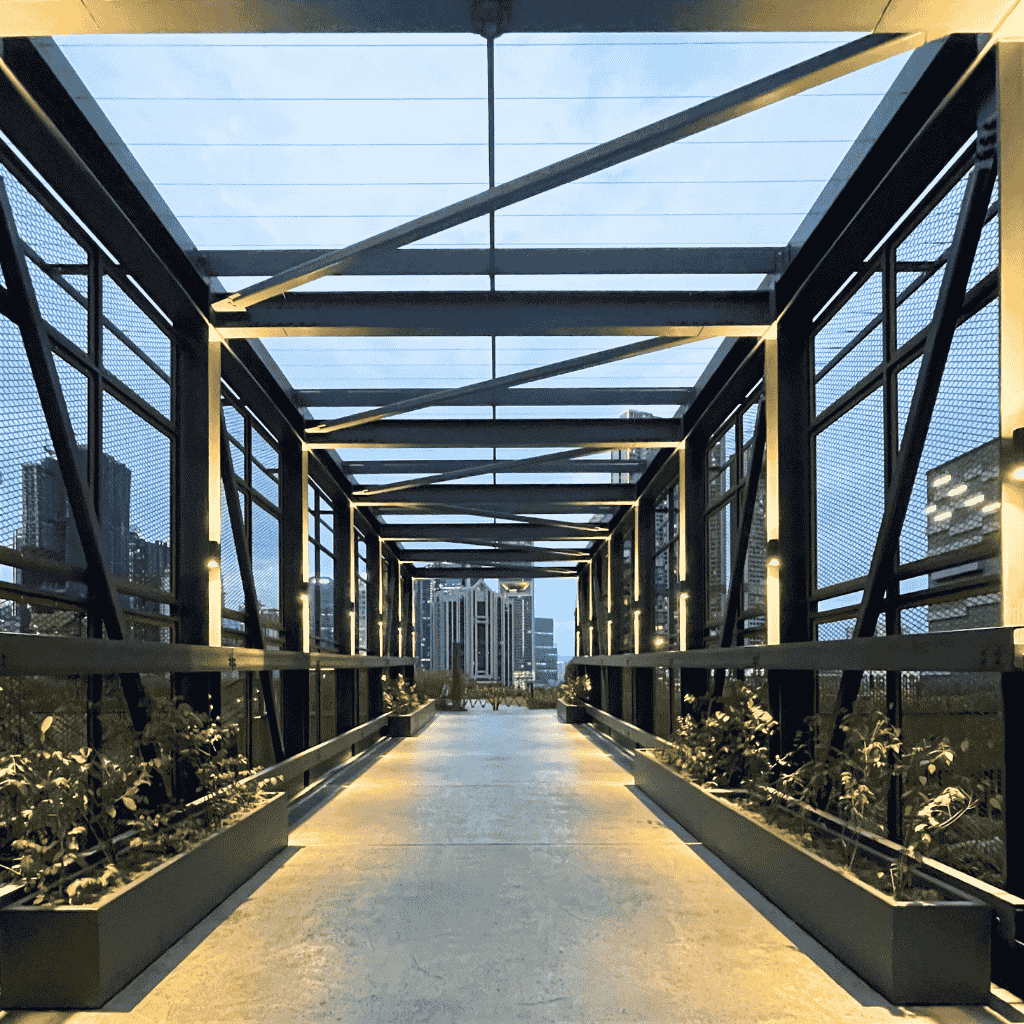 A lit modern pedestrian bridge at dusk with city buildings in the background, symbolizing progress and connection — representing the journey of how I hired my first VA.