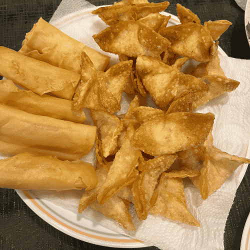 Letting go as a mother while cooking homemade snacks — crispy spring rolls and fried wontons served on a plate.
