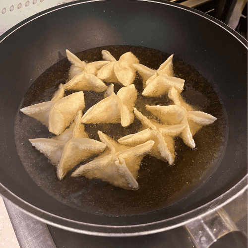 Letting go as a mother while frying homemade wontons in a pan, finding calm in simple kitchen moments.