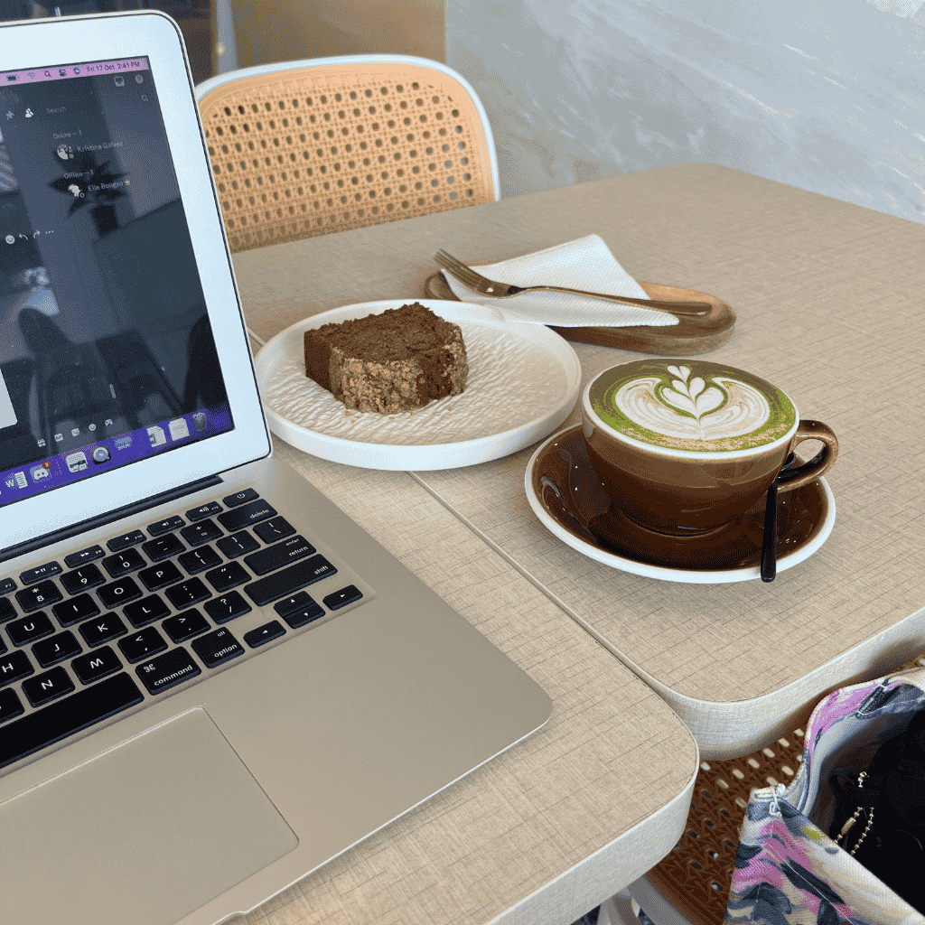 Laptop on a café table with matcha latte and cake — reflecting focus and reflection while learning from failure in your 40s.