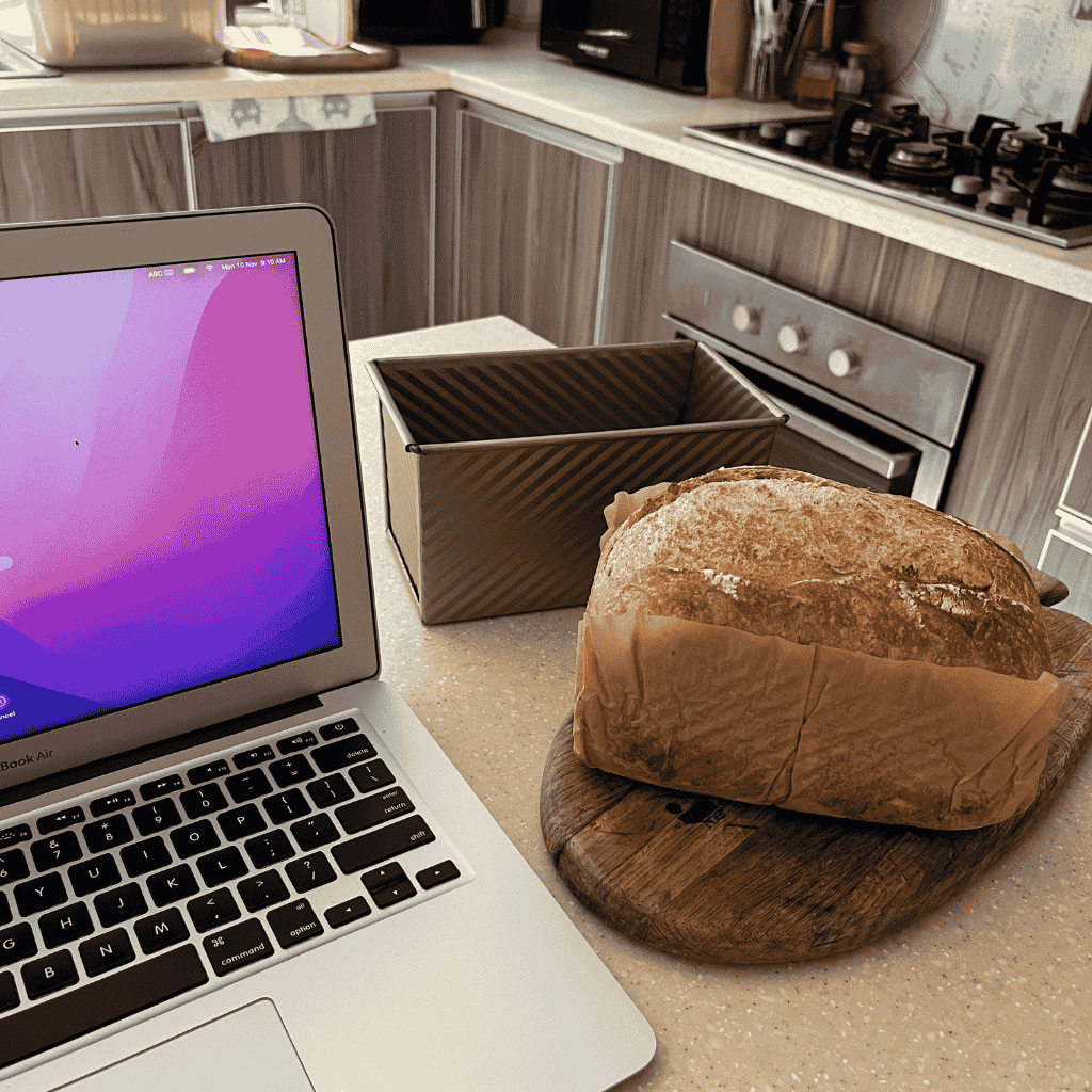 Homemade sourdough bread cooling beside a laptop during a morning inspired by the Mel Robbins Odyssey Questions.